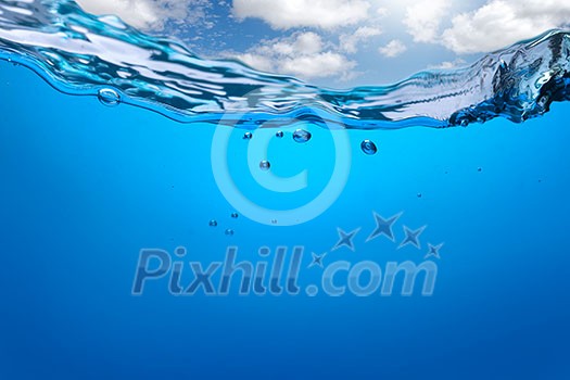 Splash of blue water with bubbles and blue sky. Underwater image