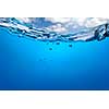 Splash of blue water with bubbles and blue sky. Underwater image
