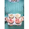 young woman holding a box of colorful cupcakes decorated with hearts and stars