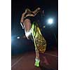 woman  sprinter leaving starting blocks on the athletic  track. Side view. exploding start
