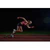 woman  sprinter leaving starting blocks on the athletic  track. Side view. exploding start