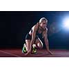woman  sprinter leaving starting blocks on the athletic  track. Side view. exploding start