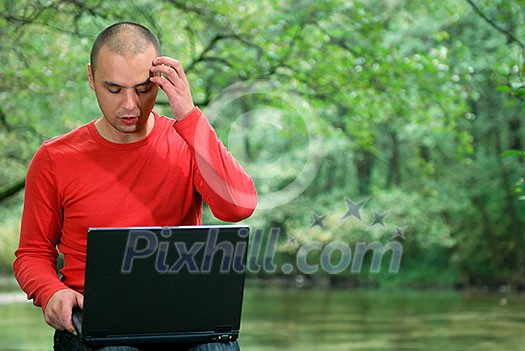 one young businessman working on laptop outdoor with green nature in background one young businessman working on laptop outdoor with green nature in background