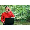 one young businessman working on laptop outdoor with green nature in background