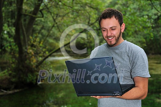 one young businessman working on laptop outdoor with green nature in background one young businessman working on laptop outdoor with green nature in background