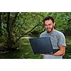 one young businessman working on laptop outdoor with green nature in background