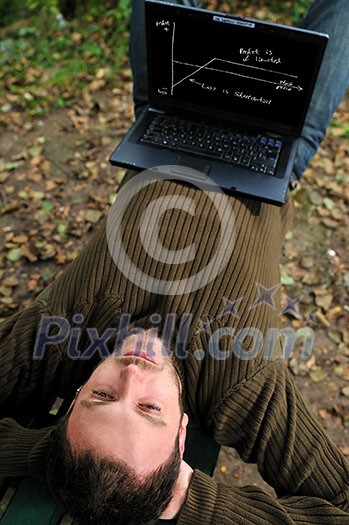 one young businessman working on laptop outdoor with green nature in background one young businessman working on laptop outdoor with green nature in background