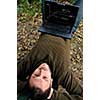 one young businessman working on laptop outdoor with green nature in background