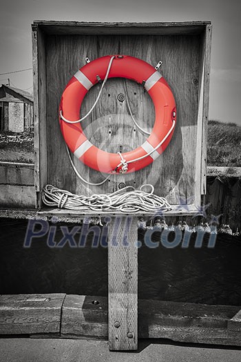 Orange life saver or buoy hanging in wooden box on dock. Prince Edward Island, Canada, selective coloring. Orange life saver or buoy hanging in wooden box on dock. Prince Edward Island, Canada, selective coloring.