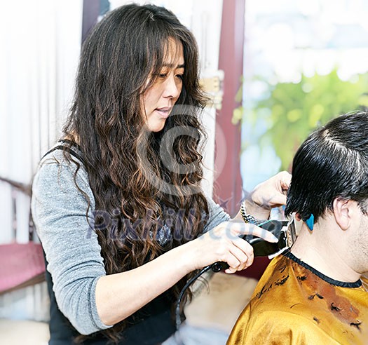 Hairdresser cutting hair in her salon with trimmer Hairdresser cutting hair in her salon with trimmer