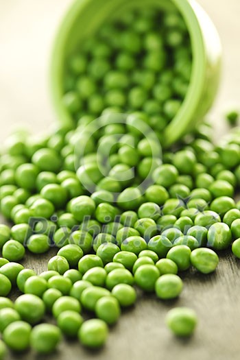 Closeup on spilling bowl of fresh green green peas