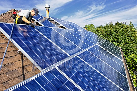 Man installing alternative energy photovoltaic solar panels on roof Man installing alternative energy photovoltaic solar panels on roof