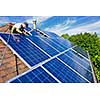 Man installing alternative energy photovoltaic solar panels on roof