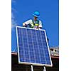 Man installing alternative energy photovoltaic solar panels on roof