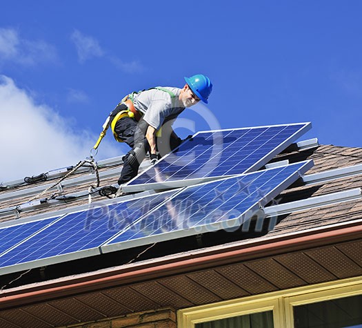 Man installing alternative energy photovoltaic solar panels on roof Man installing alternative energy photovoltaic solar panels on roof