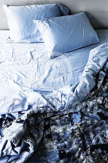 Unmade messy bed with wrinkled sheets from above Unmade messy bed with wrinkled sheets from above