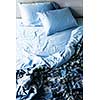 Unmade messy bed with wrinkled sheets from above