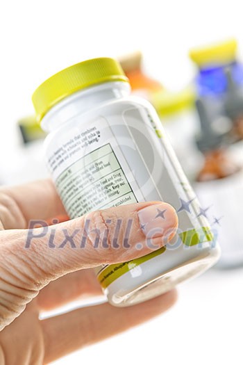 Hand holding medicine bottle to read label Hand holding medicine bottle to read label