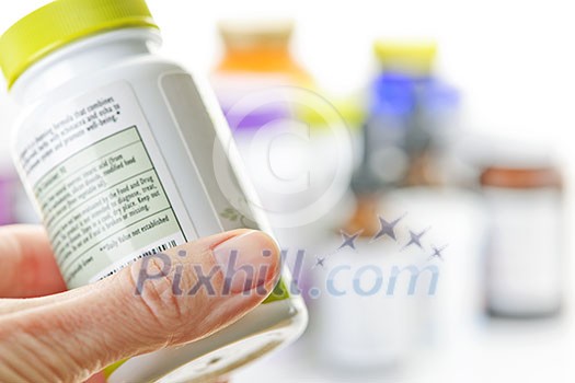 Hand holding medicine bottle to read label Hand holding medicine bottle to read label