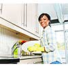 Happy smiling young black woman enjoying washing dishes in kitchen