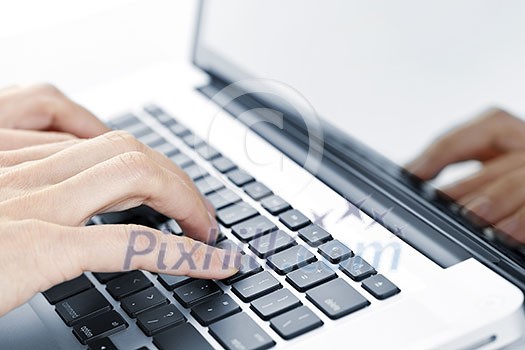 Hands typing on laptop computer keyboard close up