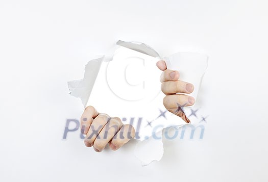 Hands ripping a hole in white paper with torn edges Hands ripping a hole in white paper with torn edges