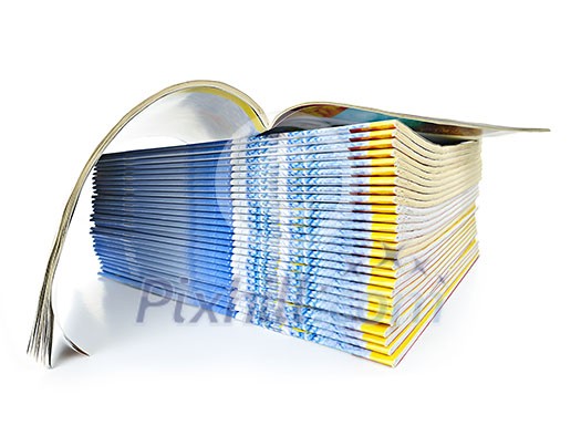 Many magazines stacked in a pile with one open isolated on white Many magazines stacked in a pile with one open isolated on white