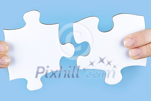 Fingers joining large white blank jigsaw puzzle pieces Fingers joining large white blank jigsaw puzzle pieces