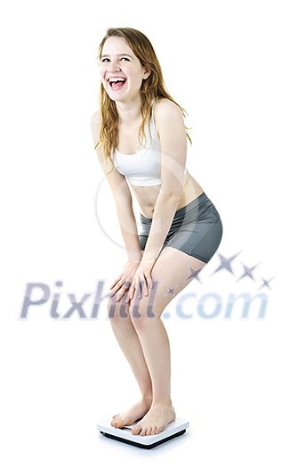 Happy laughing young woman standing on bathroom scale isolated on white Happy laughing young woman standing on bathroom scale isolated on white