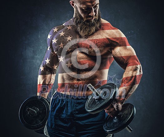 Power athletic bearded man in training pumping up muscles with dumbbell. The body is depicted an American flag. Concept: Captain America.