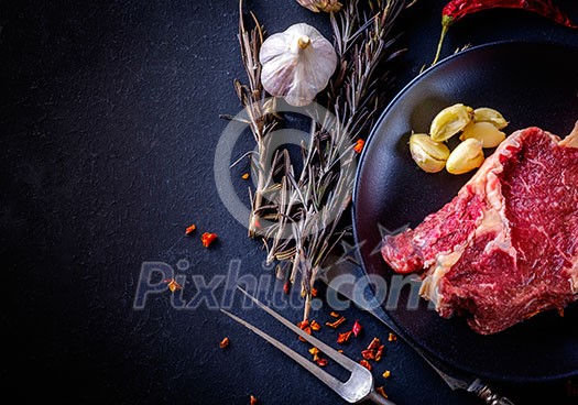 Raw meat steak entrecote on the plate with spice on the dark table Raw meat steak entrecote on the plate with spice on the dark table