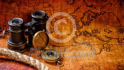 Old vintage retro compass and binoculars on ancient world map. Vintage still life. Travel geography navigation concept background.