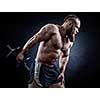 Strong bodybuilder with six pack, perfect abs, shoulders, biceps, triceps and chest. Power athletic bearded man in training pumping up muscles with dumbbell. 