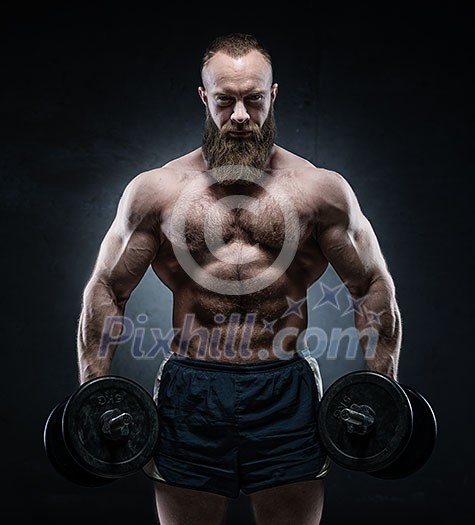 Bearded Muscular bodybuilder posing with heavy dumbbells on grunge background. Bearded Muscular bodybuilder posing with heavy dumbbells on grunge background.