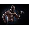 Strong bodybuilder with six pack, perfect abs, shoulders, biceps, triceps and chest. Power athletic bearded man in training pumping up muscles with dumbbell. 