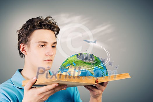 Young man in casual holding opened book with city model. Elements of this image are furnished by NASA Young man in casual holding opened book with city model. Elements of this image are furnished by NASA