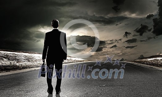 Back view of businessman standing on road and looking far away Back view of businessman standing on road and looking far away