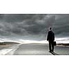 Back view of businessman standing on road and looking far away