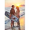 romantic couple in surf wear posing at beach on sunset at summer season