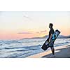 Portrait of a strong young  surf  man at beach on sunset in a contemplative mood with a surfboard