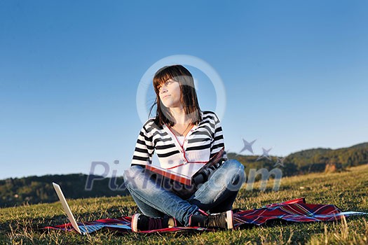 young teen girl read book and study homework outdoor in nature with blue sky in background young teen girl read book and study homework outdoor in nature with blue sky in background