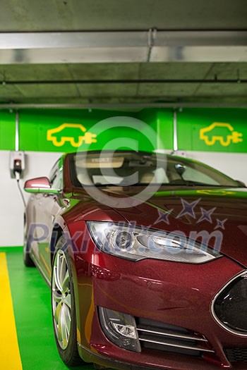 Electric car at a charging point in an underground parking (shallow DOF; color toned image) Electric car at a charging point in an underground parking (shallow DOF; color toned image)