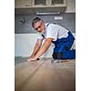 DIY, repair, building and home concept - close up of male hands lying parquet floor board/laminate flooring (shallow DOF; color toned image)