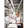 Pretty, young woman choosing the right pillow for her bed in a modern home furnishings store (color toned image; shallow DOF)