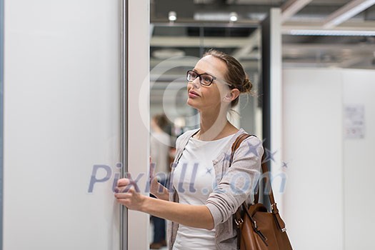 Pretty, young woman choosing the right furniture for her apartment in a modern home furnishings store (color toned image; shallow DOF) Pretty, young woman choosing the right furniture for her apartment in a modern home furnishings store (color toned image; shallow DOF)