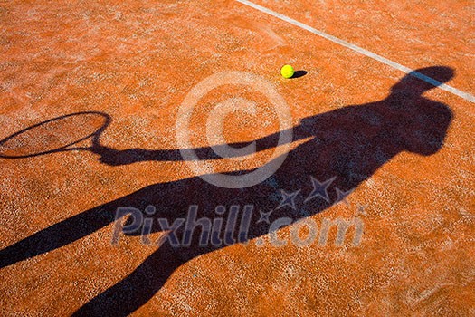 Shadow of a tennis player in action on a tennis court (conceptual image with a tennis ball lying on the court and the shadow of the player positioned in a way he seems to be playing it) Shadow of a tennis player in action on a tennis court (conceptual image with a tennis ball lying on the court and the shadow of the player positioned in a way he seems to be playing it)