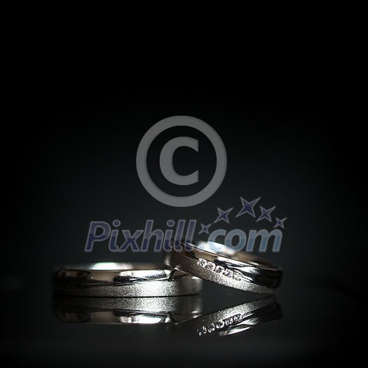 Wedding day details - two lovely golden wedding rings awaiting their moment, with some nice reflections Wedding day details - two lovely golden wedding rings awaiting their moment, with some nice reflections