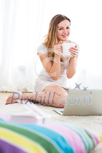 Pretty, young woman using a laptop computer at home, sitting on a rug, chatting via social networks/shopping online/working Pretty, young woman using a laptop computer at home, sitting on a rug, chatting via social networks/shopping online/working