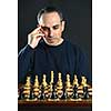Man looking at wooden chess board thinking about first move