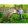 Man watering the garden with hose in backyard